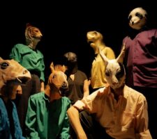 group photo of 7 people with animal heads (horse, giraffe, tiger, bear, bird, turtle, cat)